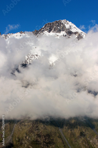 Snow covered mountains behind white clouds in Stepantsminda, Caucasus, Georgia