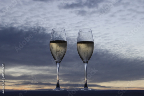 Two glasses of champagne at sunset with a sky background