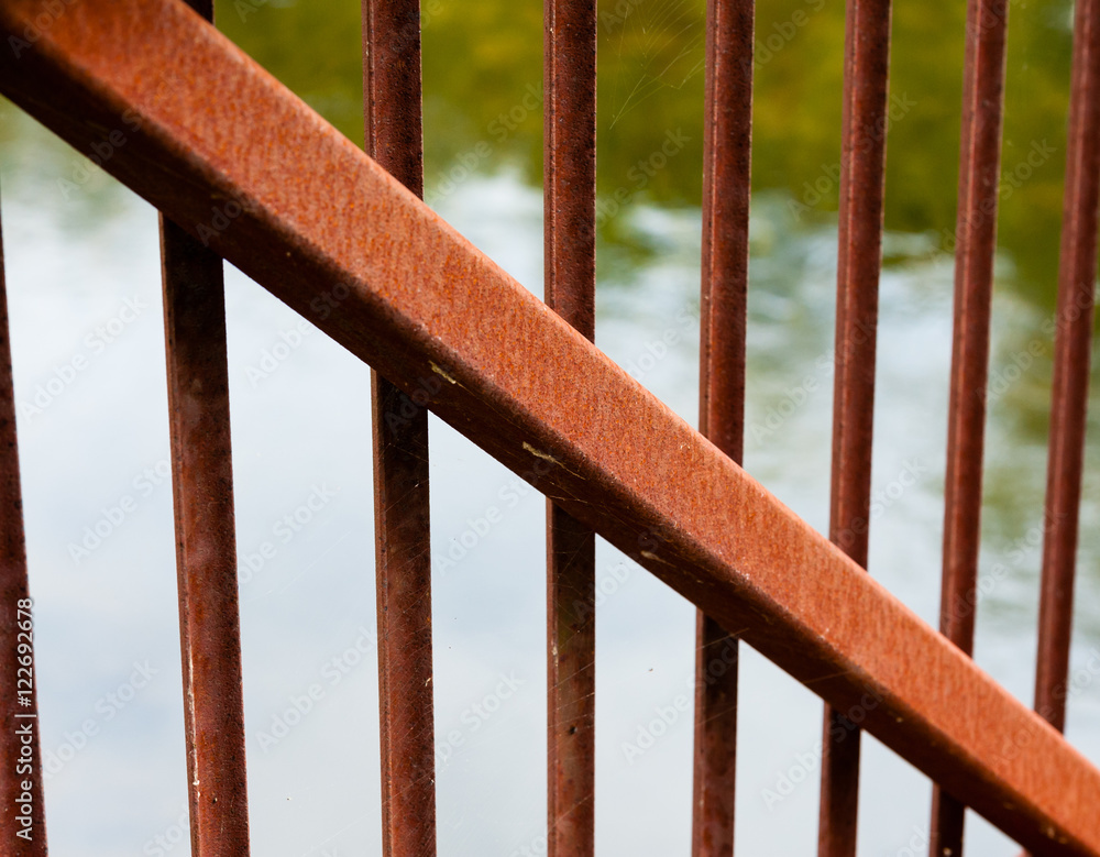 Rusted metal beam diagonal across smaller bars. Rusted metal beam diagonal across smaller bars.
