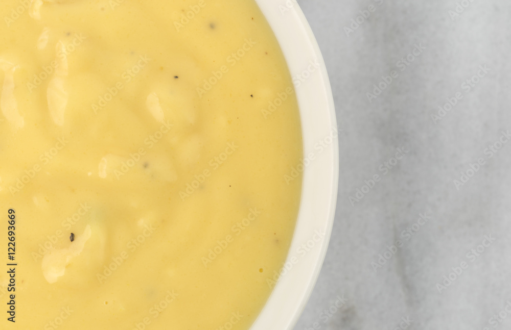 Cheddar potato soup in a bowl on a marble table top close view. Cheddar potato soup in a bowl on a marble table top close view.