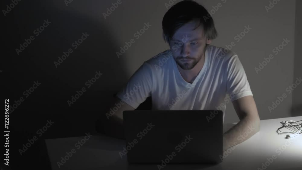 Businessman working with computer at night, busy and tired freelancer with red eyes, blue screen from laptop. Businessman working with computer at night, busy and tired freelancer with red eyes, blue screen from laptop.