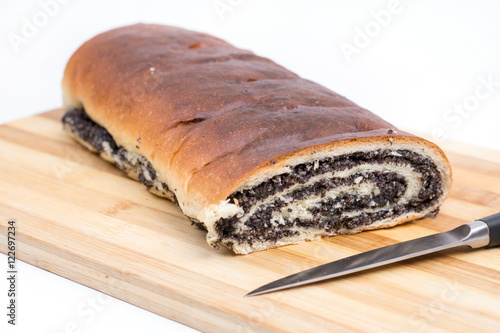 Strudel with poppy seeds on the wooden board with knife