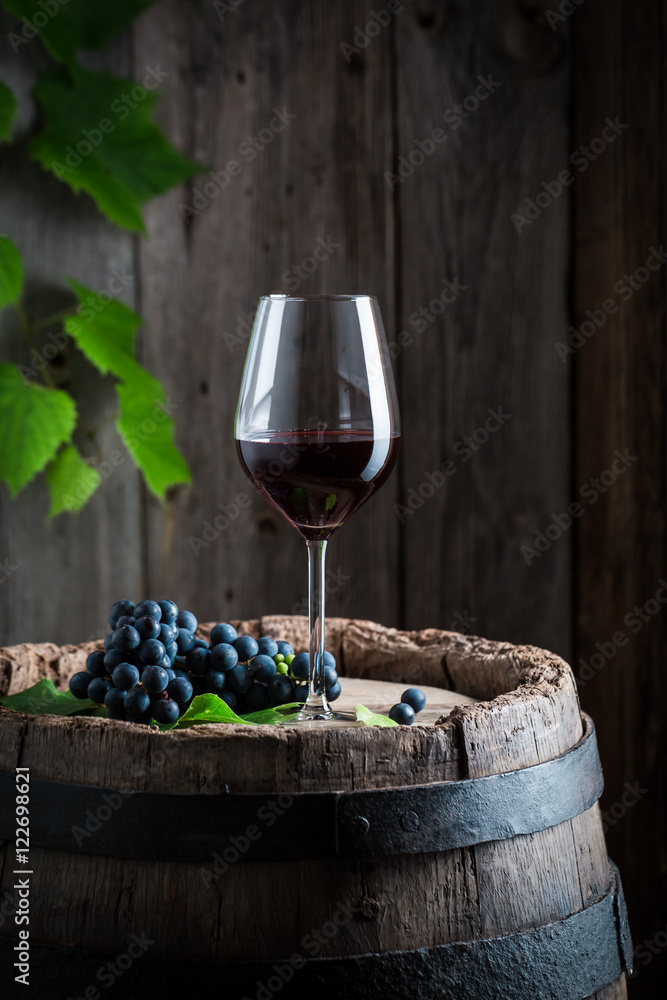 Fresh red wine on barrel with grapes