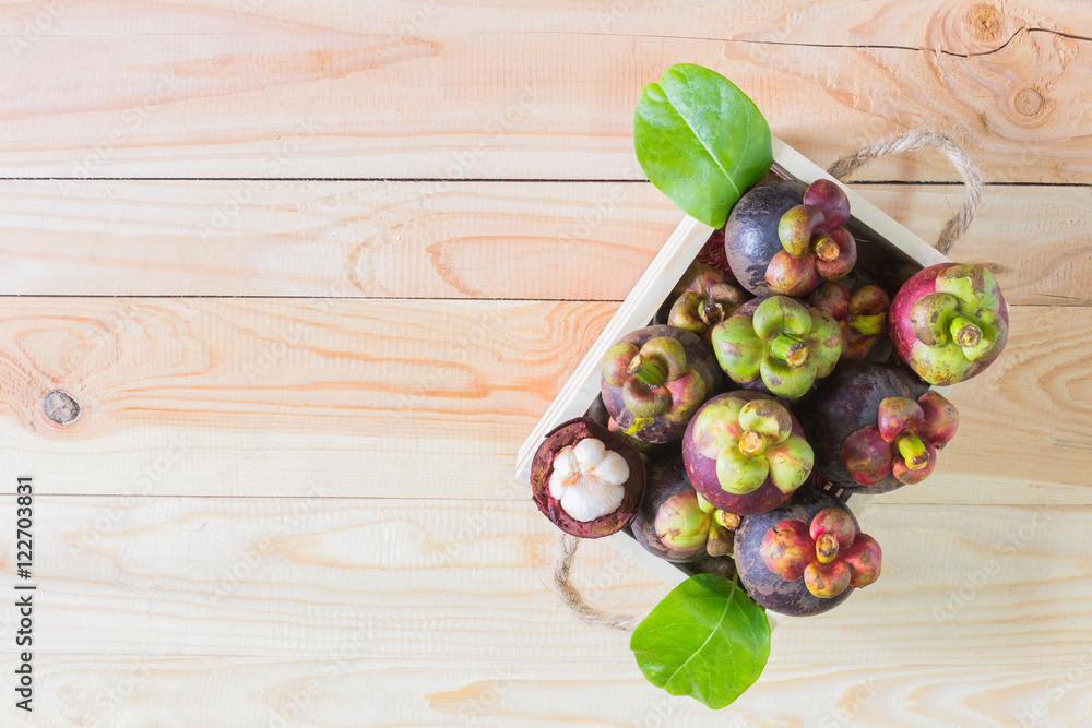 Mangosteen on wooden box, top view background.