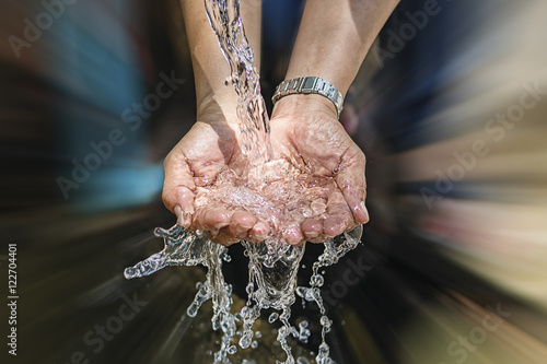 Spring water flows from the pipe into the hands photo