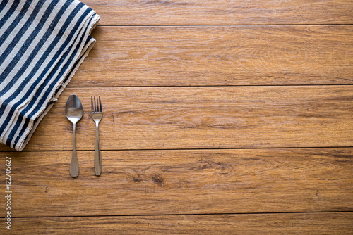 white plate and fork on old wooden table with checked tablecloth