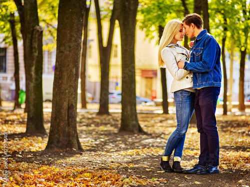 Young couple kissing in autumn park . Loving couple kissing in sun autumn park. Fall weather is crisp although shines bright autumn sun. © Gennadiy Poznyakov