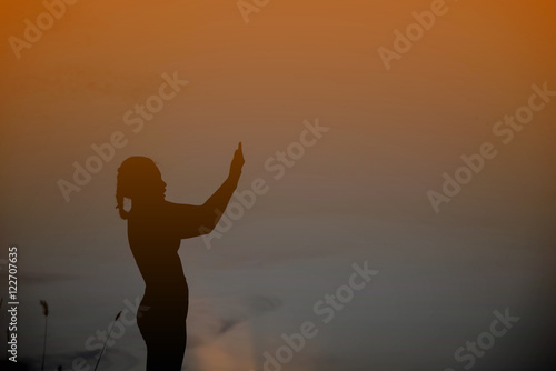 silhouette young woman alone with God at sunset