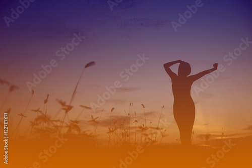 Silhouette of a young woman practicing yoga at sunset