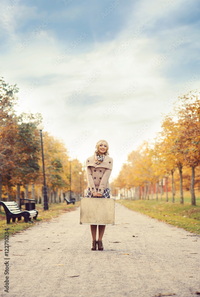 Beautiful girl with a suitcase in a park Beautiful girl with a suitcase in a park