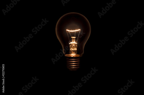 Tungsten light bulb without wiring and socket on black background. Concept for creative idea.
