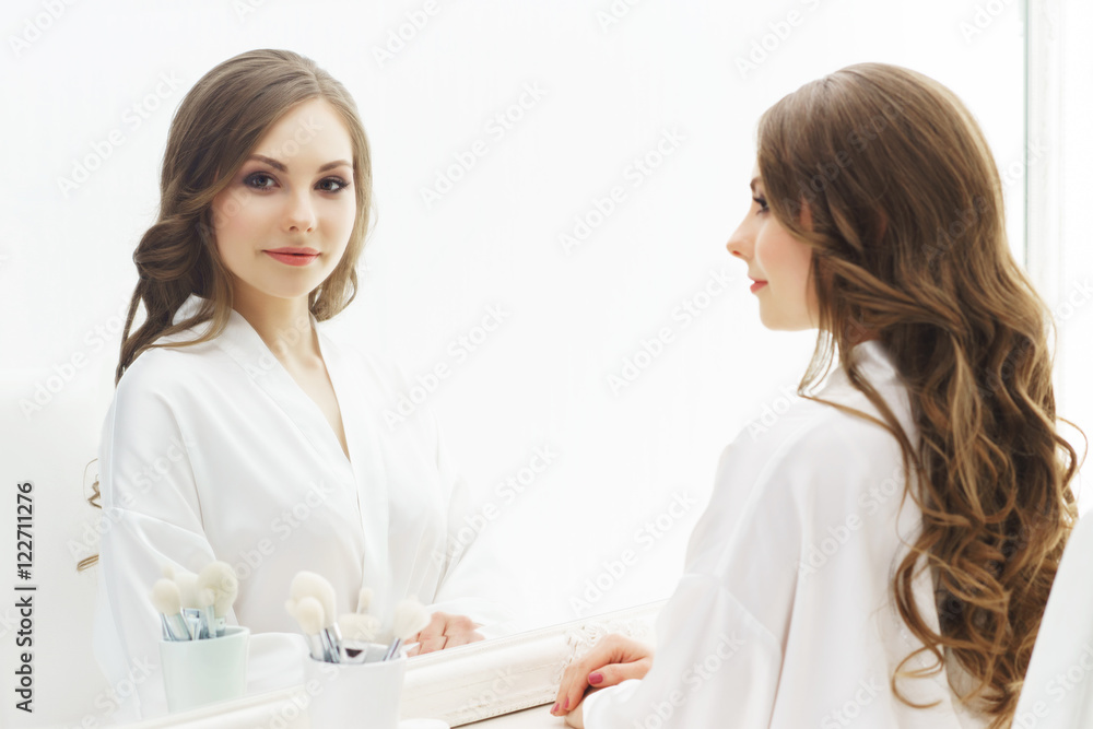 Young woman applying makeup in a studio Young woman applying makeup in a studio
