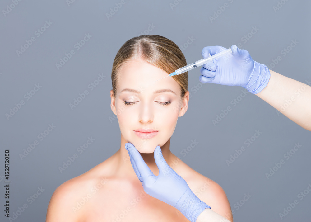 Doctor injecting botox into face of a young woman Doctor injecting botox into face of a young woman