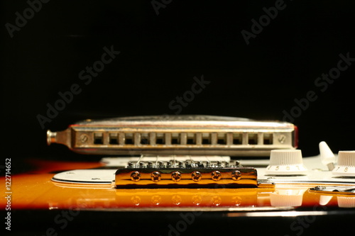 Vintage electric guitar with harmonica on black background