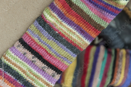 Striped colorful woolen knitted fabric closeup on brown cardboard. Blurred background.