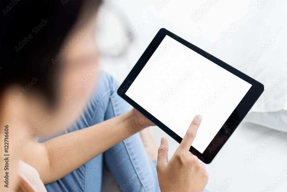 Woman using digital tablet on bed.