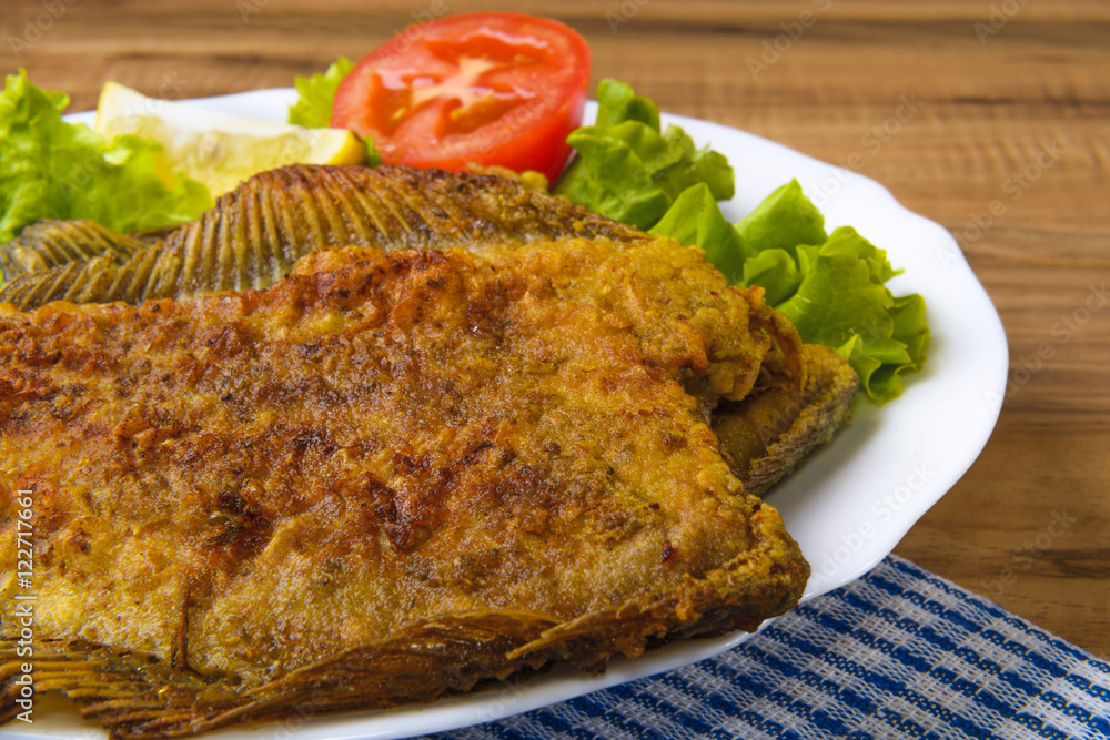 Fried Fish flounder on white plate with lettuce and lemon Fried Fish flounder on white plate with lettuce and lemon