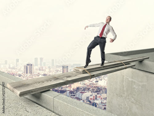 businessman crosses  improvised bridge. concept caution, danger challenge