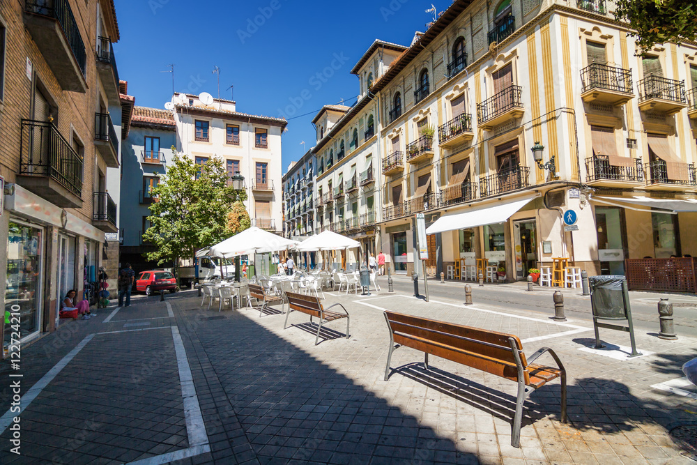 Sunny view of square and benches in the street of Granada, Andalusia province, Spain.