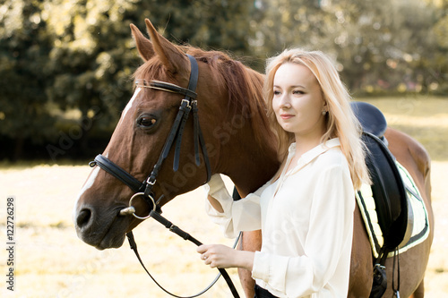 Девушка стоит рядом с коричневой лошадью