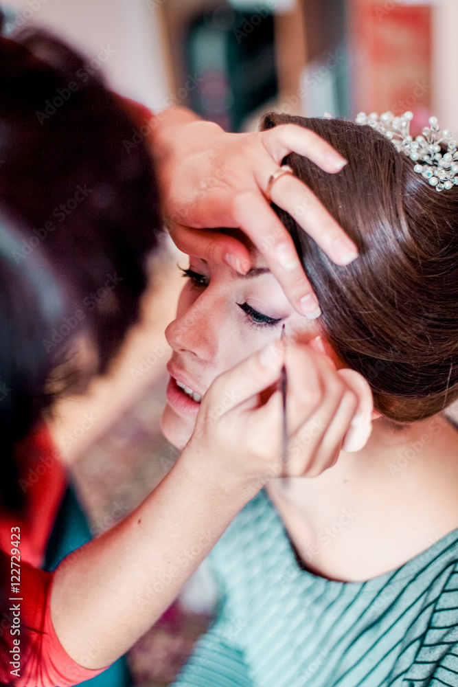 Fototapeta premium Beautiful young bride with wedding makeup and hairstyle in bedroom, newlywed woman final preparation for wedding. Happy Bride waiting groom. Marriage Wedding day moment. Bride portrait soft focus