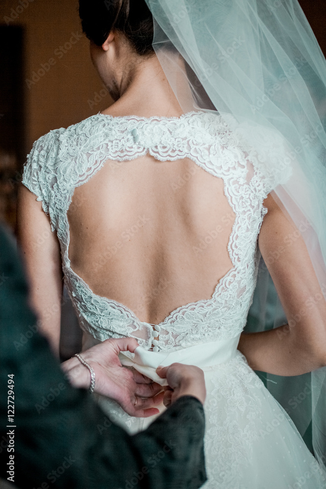 Wedding. Bridesmaid preparing bride for the wedding day. Bridesmaid helps fasten a wedding dress the bride before the ceremony. Luxury bridal dress close up. Best wedding morning. Wedding concept