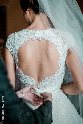 Obraz na płótnie Wedding. Bridesmaid preparing bride for the wedding day. Bridesmaid helps fasten a wedding dress the bride before the ceremony. Luxury bridal dress close up. Best wedding morning. Wedding concept w salonie