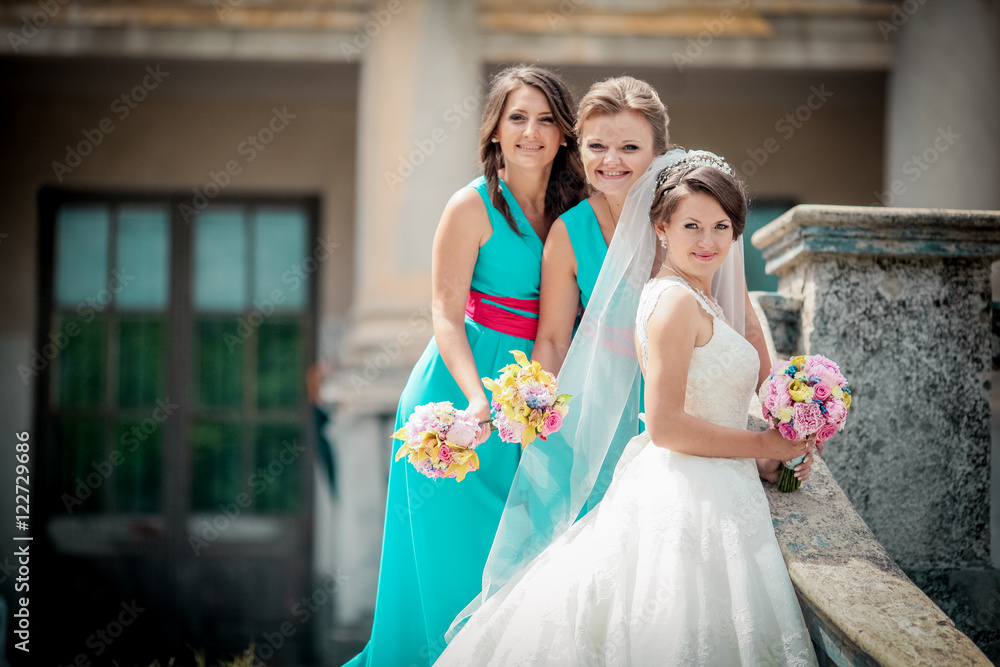Naklejka premium Beautiful brunette bride and gorgeous bridesmaids with bouquets posing near stairs