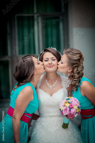 Beautiful brunette bride and gorgeous bridesmaids with bouquets posing near stairs