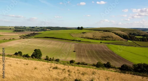 Farmer sowing seeds on field in Wiltshire, England. Tractor planting crops in field, in front of Middle Hill in the Imber Range, in the British autumn