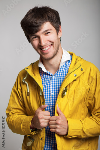 happy young man smiling in a blue plaid shirt and a yellow jacket