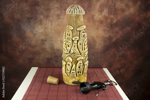 Wine bottle made of chalk stone, crockscrew and a cork on red rush mat photo