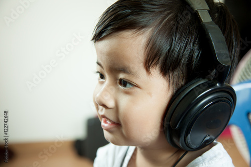 Happy Asian boy ware headphone and playing the cell phone on gra