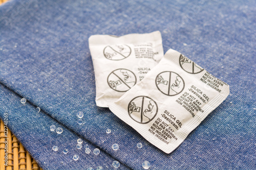 Desiccant or silica gel in paper sachet on blue fabric background