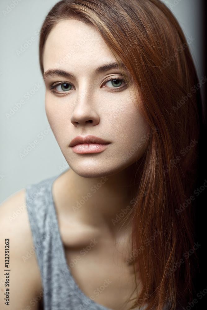 Sensual beauty portrait of a young model in tank top with red hair. Clear skin, pretty face.