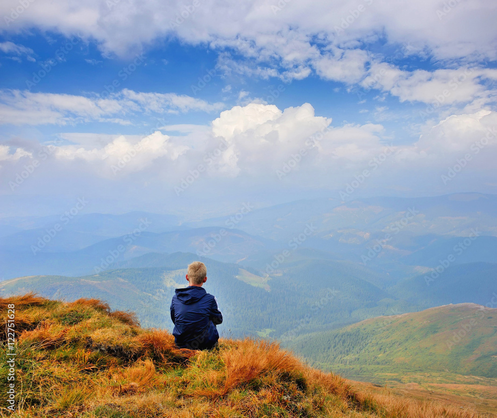 A tourist sits and looks into the distance. Man sit. Wonderful mountain landscape. Autumn is time