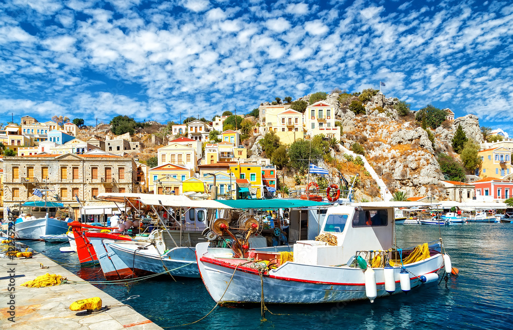 Old fishing Boats at Simi , the background of beautiful multi-colored buildings in the island