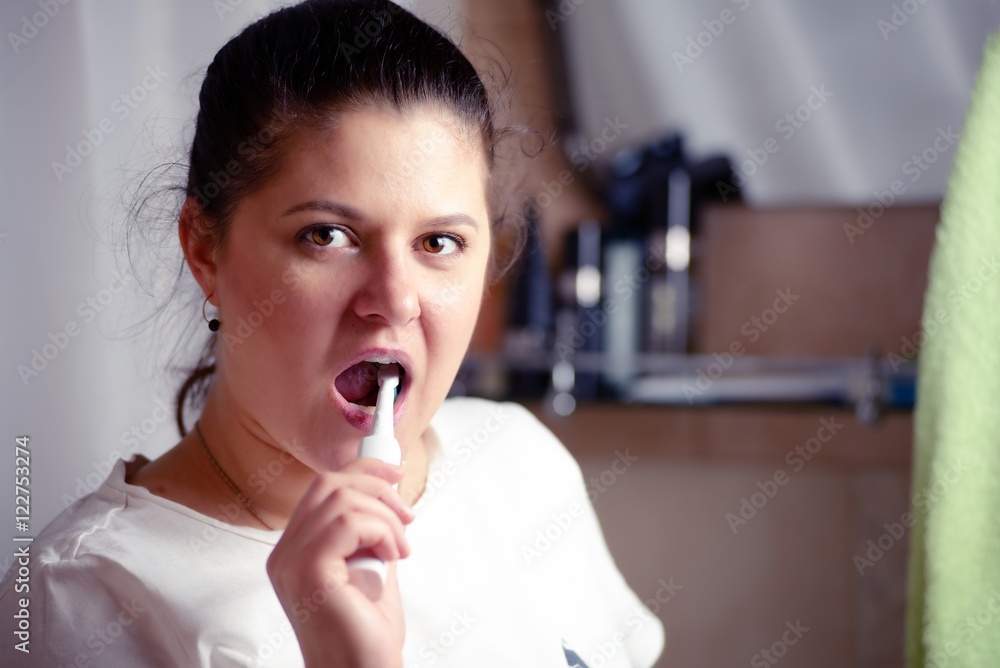 Young woman brushes teeth in bathroom an electric brush Young woman brushes teeth in bathroom an electric brush