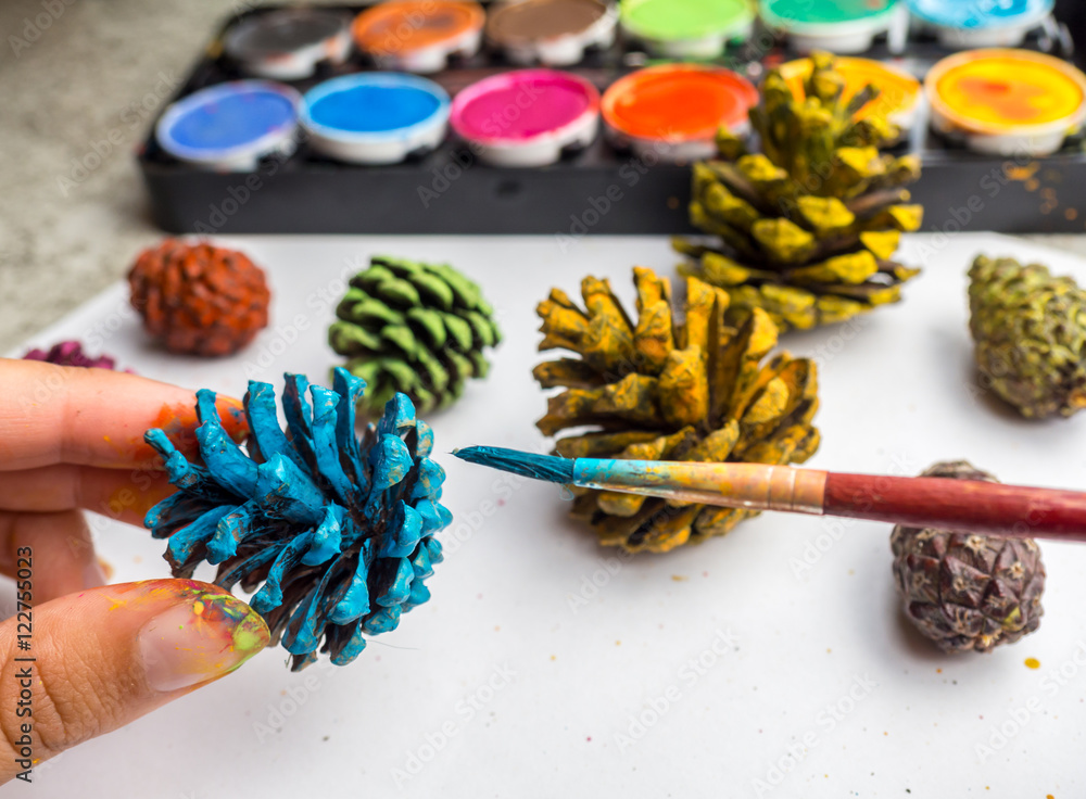 Fototapeta premium Kind malt Kiefernzapfen an