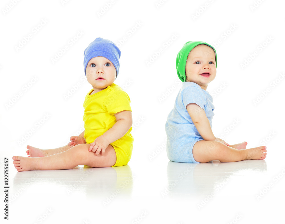 Two lovely kids in hats, sitting on the floor. isolated Two lovely kids in hats, sitting on the floor. isolated