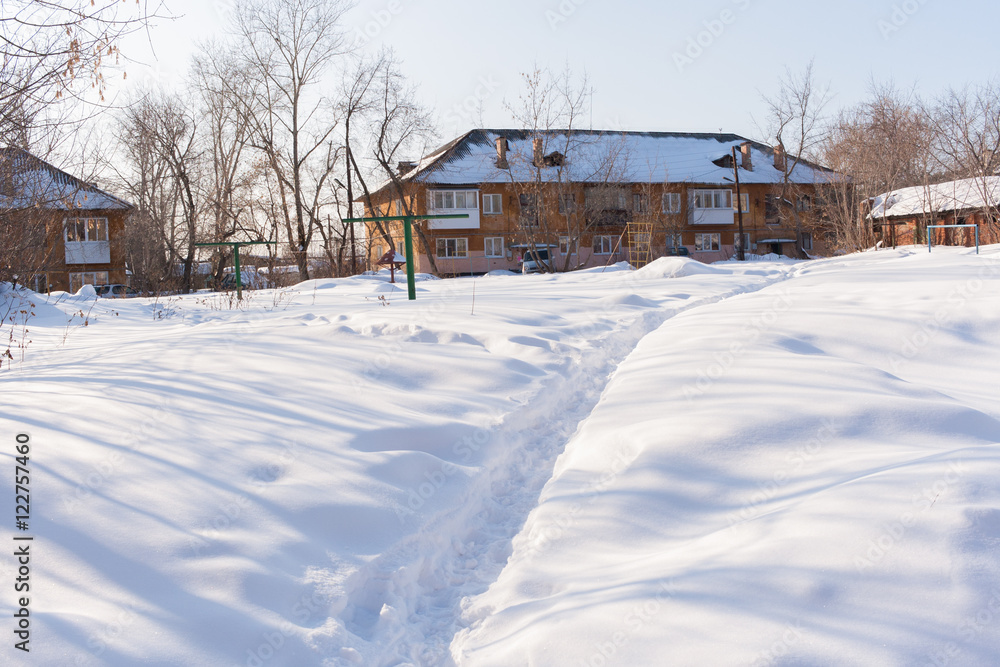 A narrow path in the white snow, leading to the two-story house.