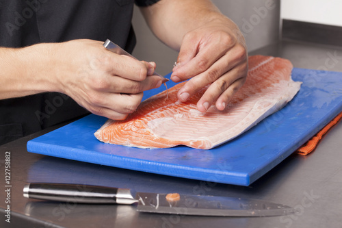 Chef removing the bones of salmon on a cutting board