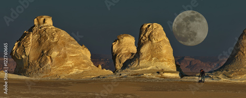 Morning in the White Desert of Egypt. Yardangs - unique chalk formation. Photographer with a camera and a tripod, a leading survey, Very big full moon. Double Exposure. photo