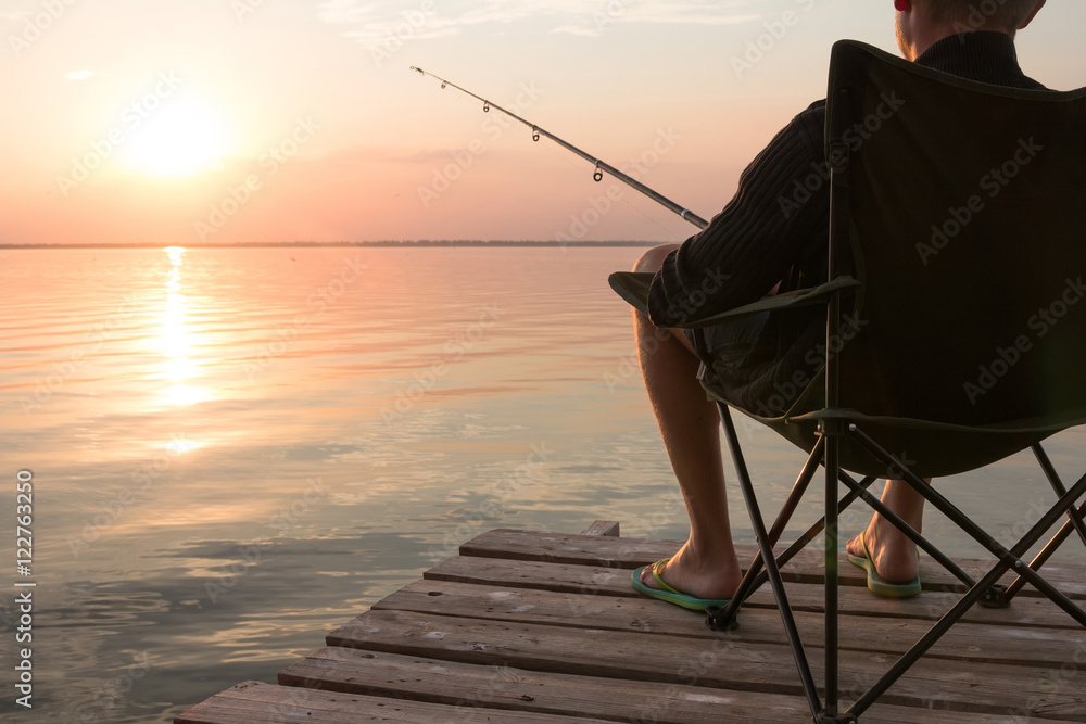 fisherman with rod over the lake at sunset fisherman with rod over the lake at sunset