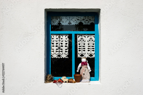 White wall of the country peasant house with a single blue windo photo