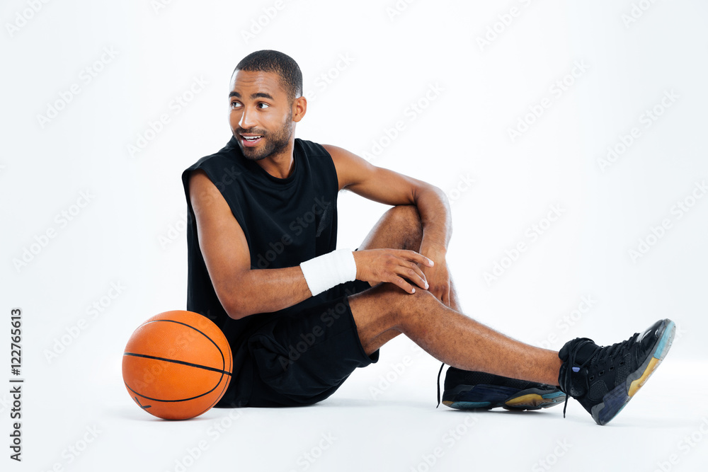 Happy young man basketball player sitting and looking away Happy young man basketball player sitting and looking away