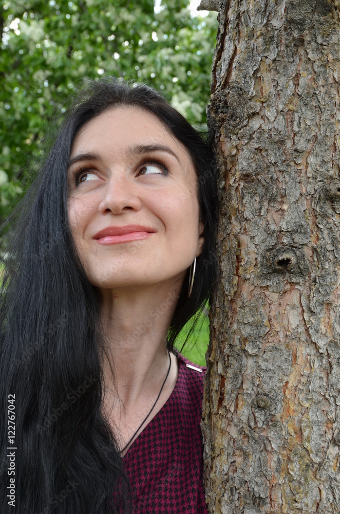brunette girl with long hair and a tree trunk, smiling girl brunette girl with long hair and a tree trunk, smiling girl