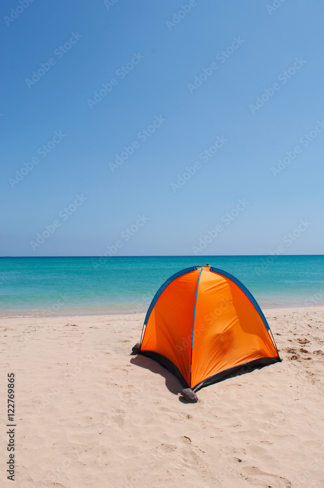 Una tenda arancione su una spiaggia bianca con acqua cristallina