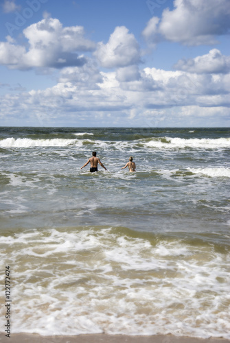 Two young people running to the blue sea
