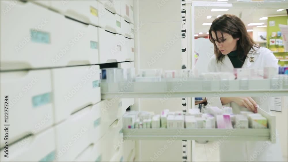 Good looking Pharmacist woman taking medicine from a drawer